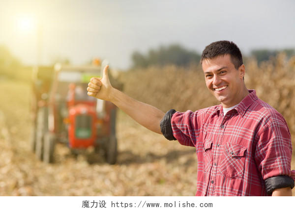年轻满意的农民竖起大拇指拖拉机在田地里加油点赞丰收的喜悦点赞手势